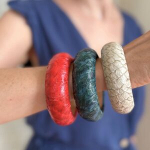 Woman with blue dress shows arm with 3 Ambani Fish Leather Bangles presented by So Rare Pieces