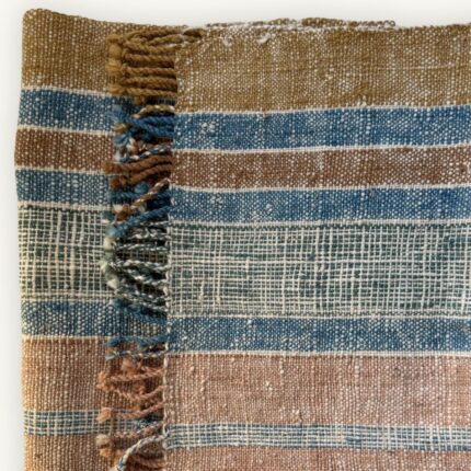 Handspun cotton in stripe pattern — indigo, copper and cream tones, hand-woven in Northeastern Thailand by women-led weaving groups. Plant-dyed. 40 × 200 cm.