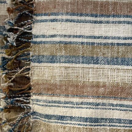 Handspun cotton in natural stripe pattern — indigo, copper and cream tones, hand-woven in Northeastern Thailand by women-led weaving groups in the Khon Kaen region. Plant-dyed. 80 × 200 cm.