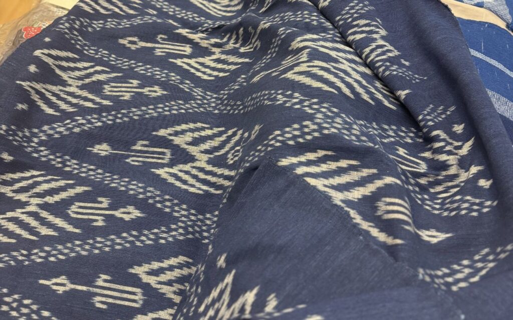 Close-up of handwoven Ikat cotton fabric in dark blue and cream, Mudmee pattern detail, handmade in Thailand