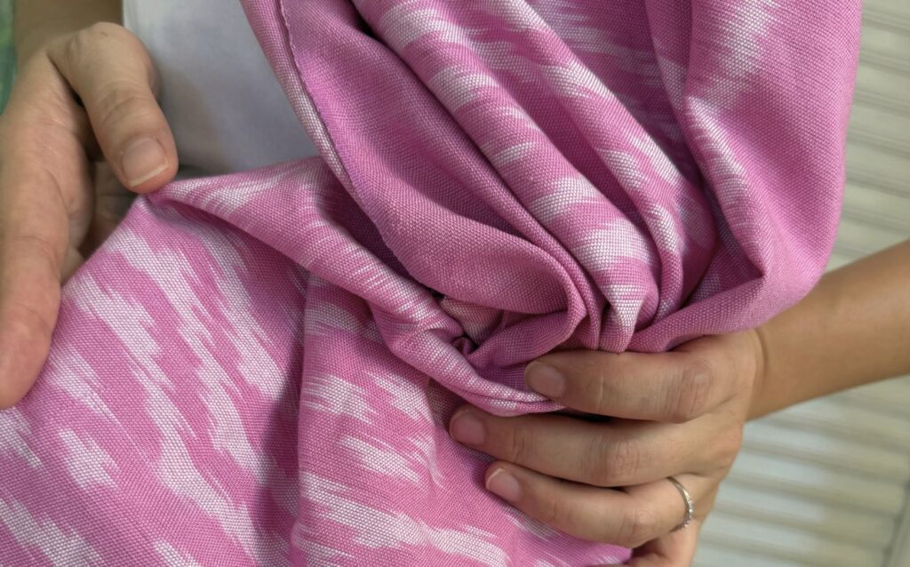 Close-up of handwoven Ikat cotton fabric in soft pink, Mudmee technique, texture detail, handmade in Thailand