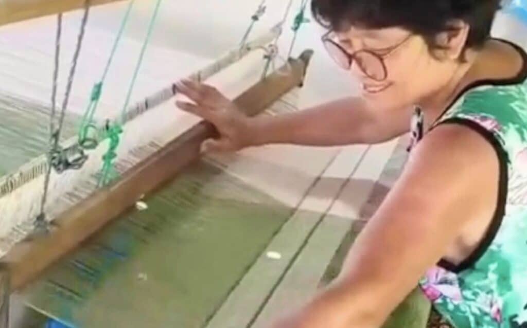 Weaver at traditional loom weaving knit pattern green