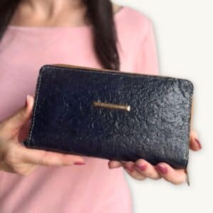 Hands holding a dark blue fish leather wallet branded with little golden tag Ambani - presented by SoRarePieces